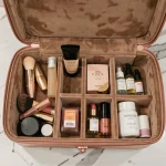 Case vanity ouverte avec compartiments organisés posée sur un comptoir en marbre dans une salle de bain d'hôtel