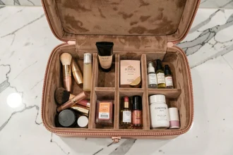 Case vanity ouverte avec compartiments organisés posée sur un comptoir en marbre dans une salle de bain d'hôtel