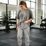 Femme en tenue de sport inadaptée dans une salle de gym moderne, illustrant les erreurs vestimentaires à éviter lors de la pratique de la gym